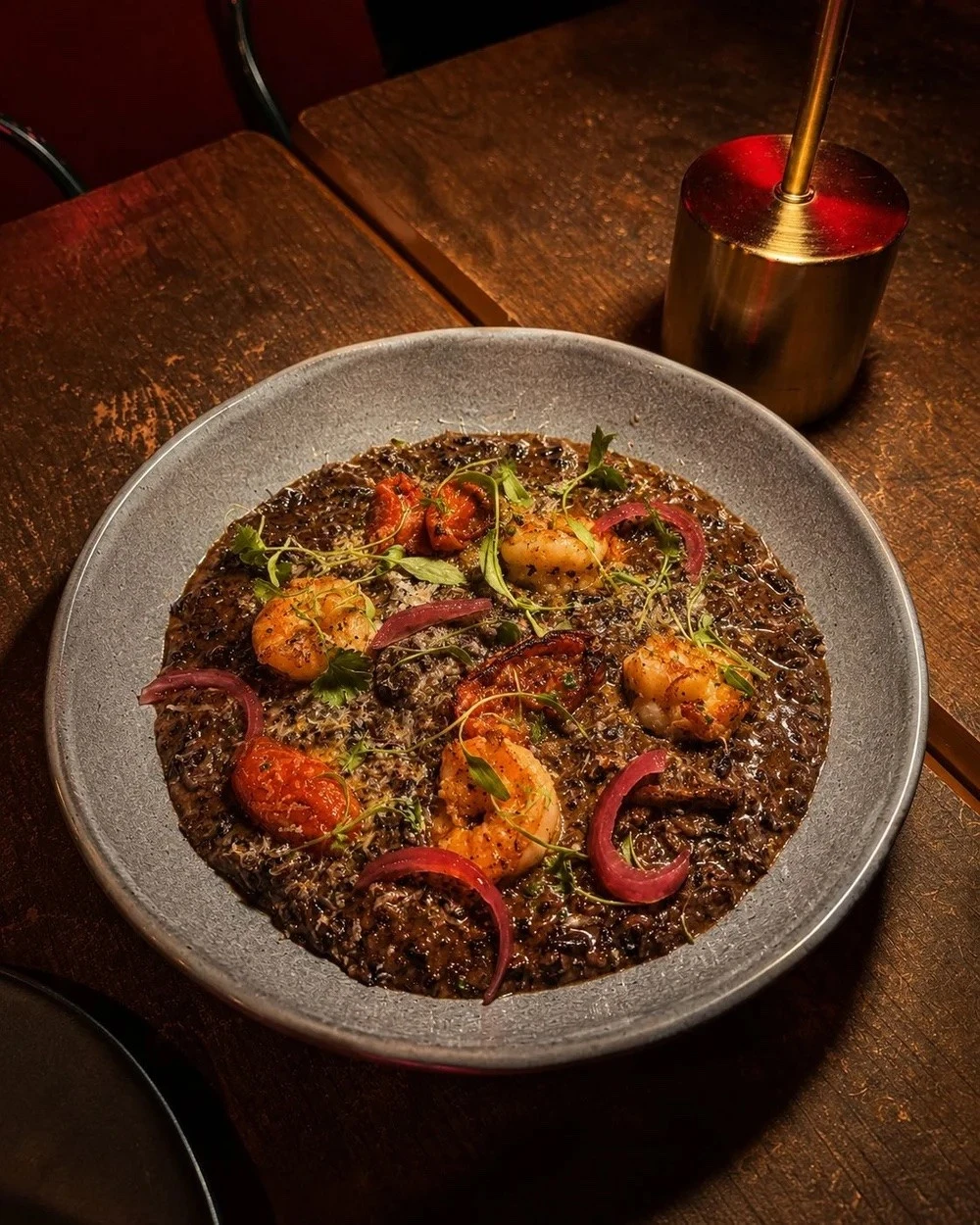 Camarão Mon Amour, arroz negro com camarões grelhados, tomate confit e salsa trufada