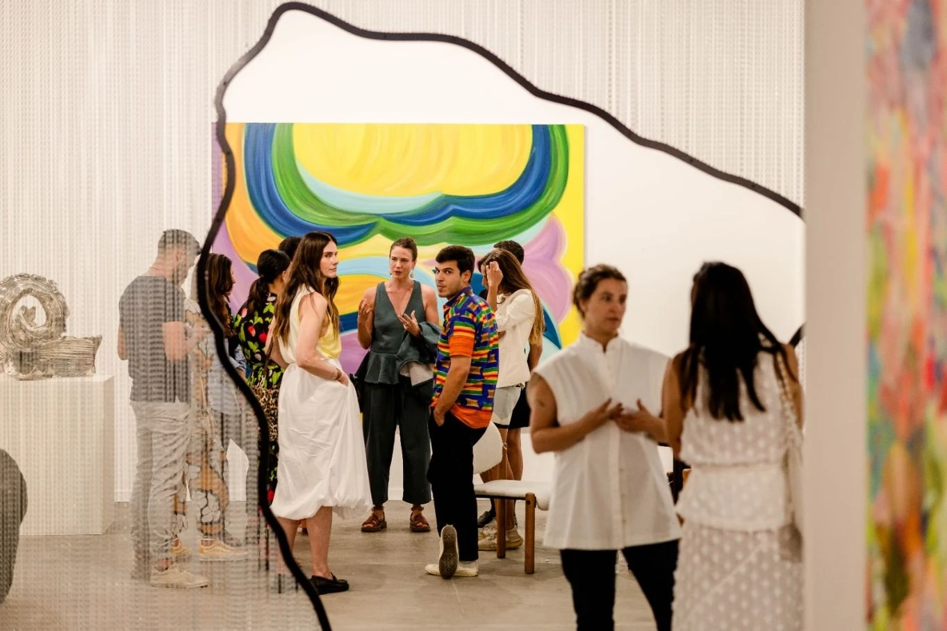 Visitantes conversam em uma galeria durante a ArtRio, diante de pinturas de grandes dimensões