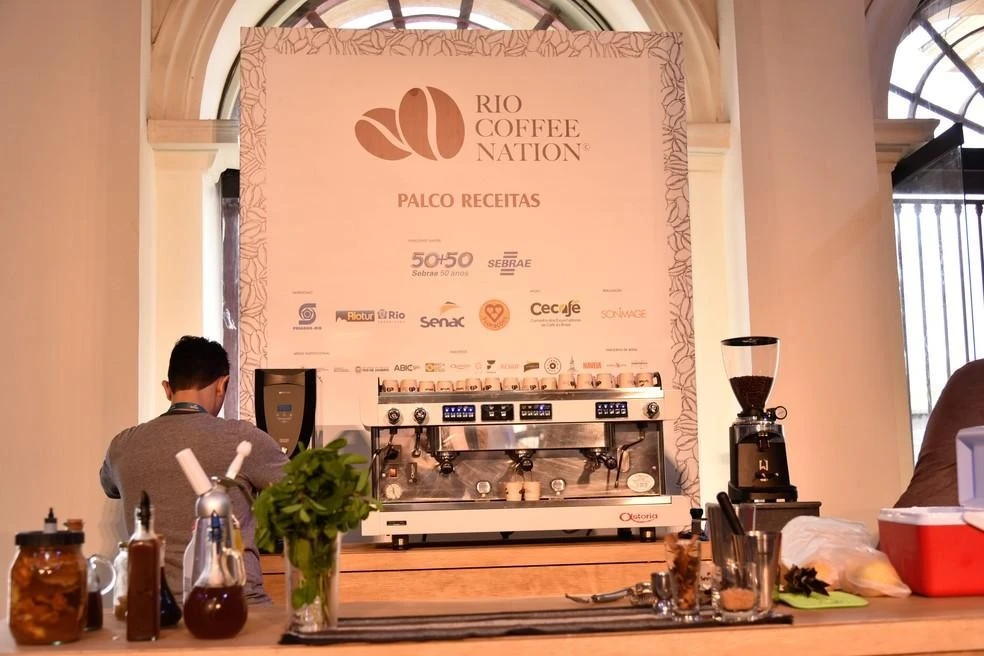 The Rio Coffee Nation recipe stage, with the event sign above the espresso machine and the grinder