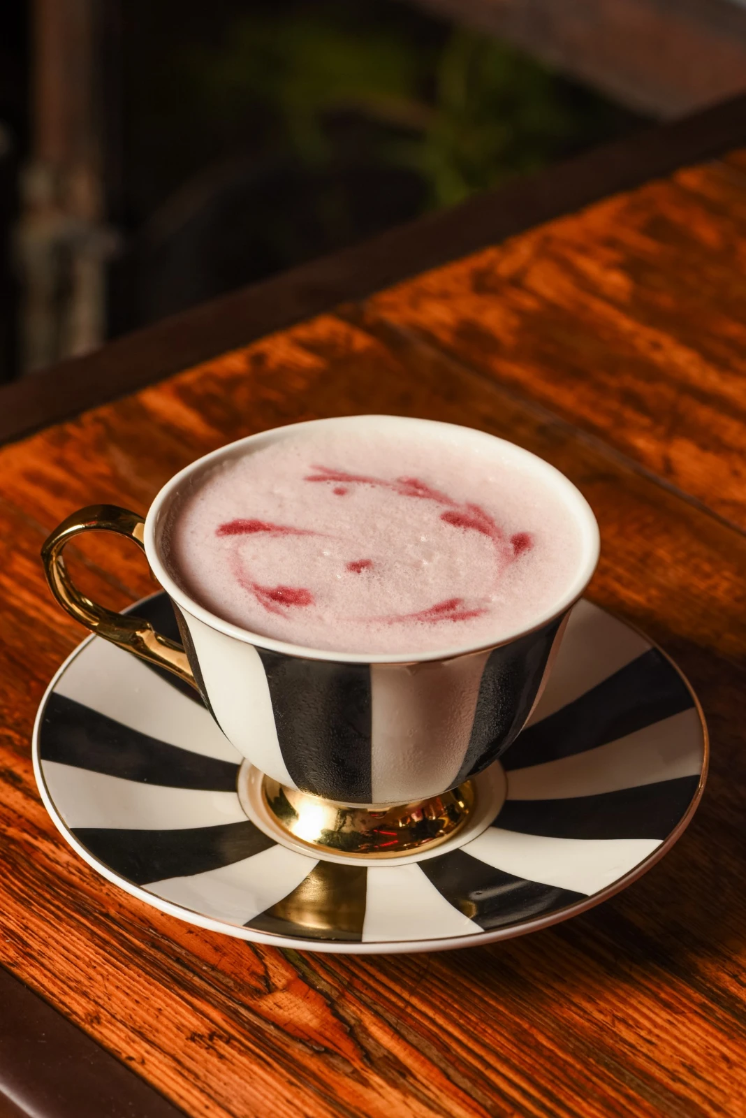 Drink Me, coquetel autoral do Surreal servido em xícara de porcelana listrada em preto e branco