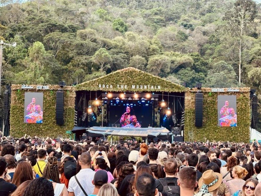 Palco principal do Rock the Mountain coberto de folhagens, com a mata da serra ao fundo e o público em frente