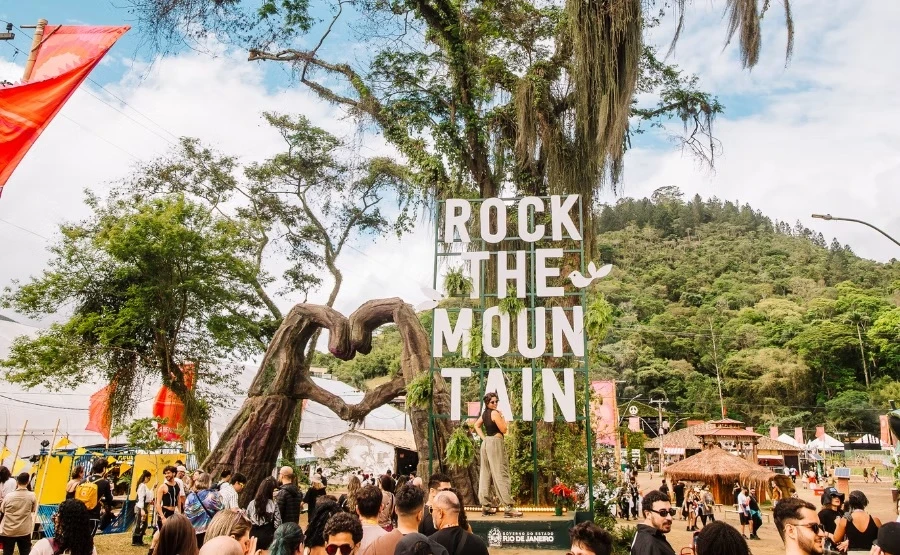Letreiro Rock the Mountain ao lado de uma escultura de coração feita de troncos, com o público circulando pelo parque