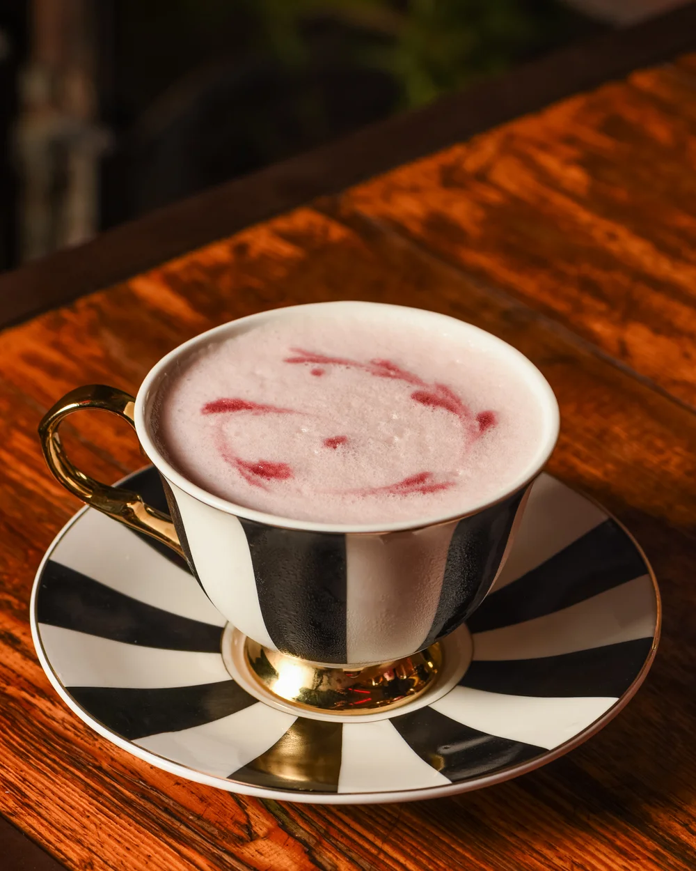 Drink Me, trago rosado servido en una taza a rayas, de la Galería Líquida de Surreal
